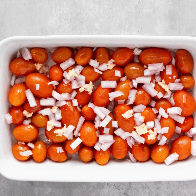 Cherry tomatoes, shallots, garlic, and olive oil tossed in a baking dish.
