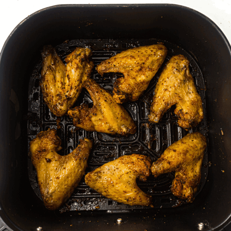 Cooked chicken wing in the air fryer basket.