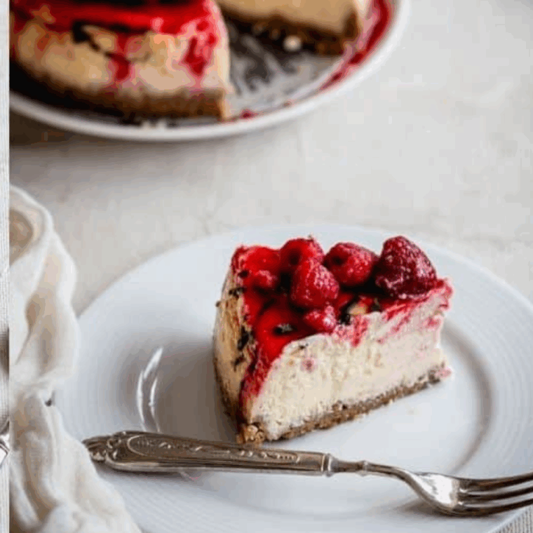 Slice of creamy Lemon Raspberry Cream Cheesecake with vibrant raspberry swirls and lemon zest garnish.
