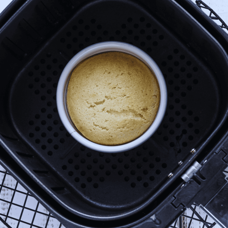 Ramekins with Boston cream pie batter cooking in the air fryer until golden and set.