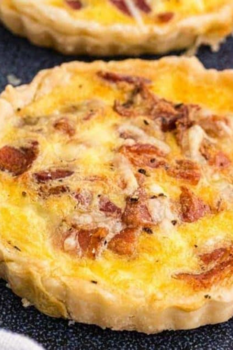 Air Fryer Bacon and Egg Quiche Lorraine with golden crust, cooked eggs, crispy bacon, and melted cheese, served in a round baking dish.