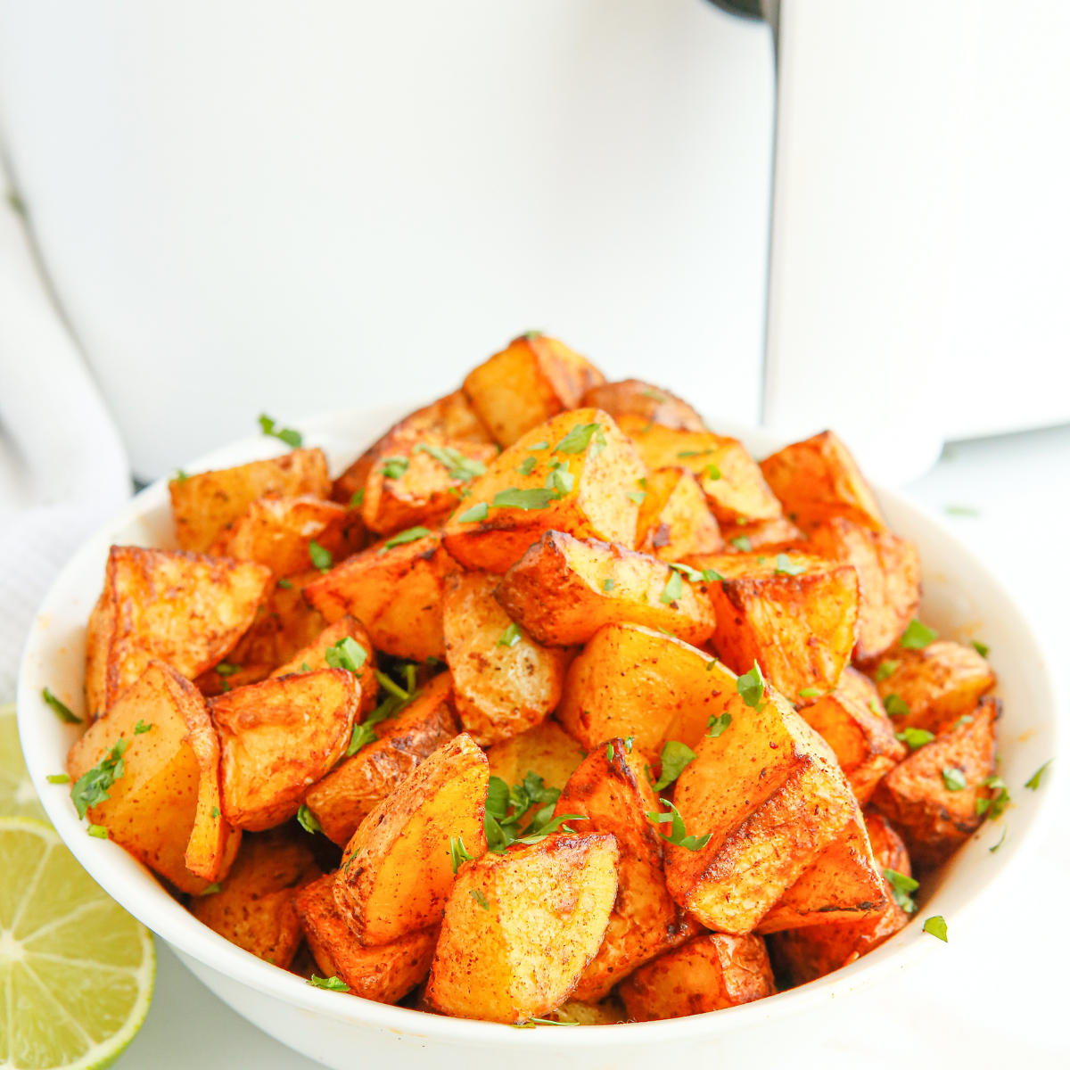 "Golden brown Air Fryer Lemon and Rosemary Roasted Potatoes garnished with fresh herbs on a white plate."