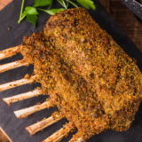 Air fryer rack of lamb with a golden garlic-herb crust, garnished with fresh rosemary on a white plate
