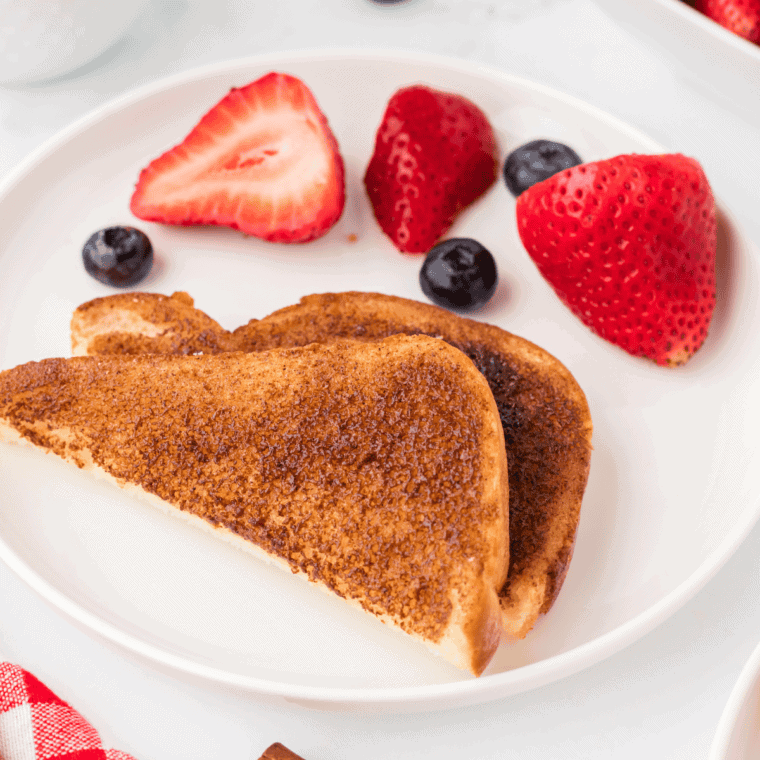 Air fryer cinnamon toast cut in half, served with strawberries and blueberries