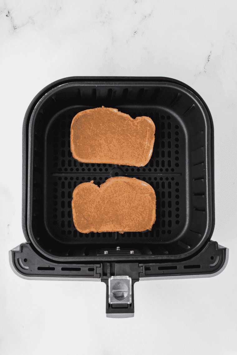 Overhead of two slices of cinnamon toast in the air fryer basket