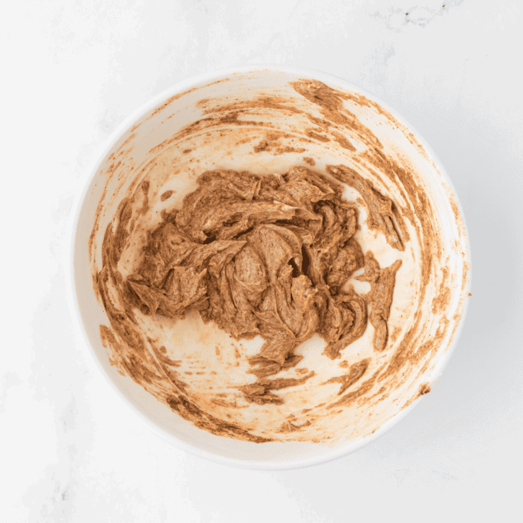 A white bowl with a mixture of cinnamon, butter, sugar and vanilla extract