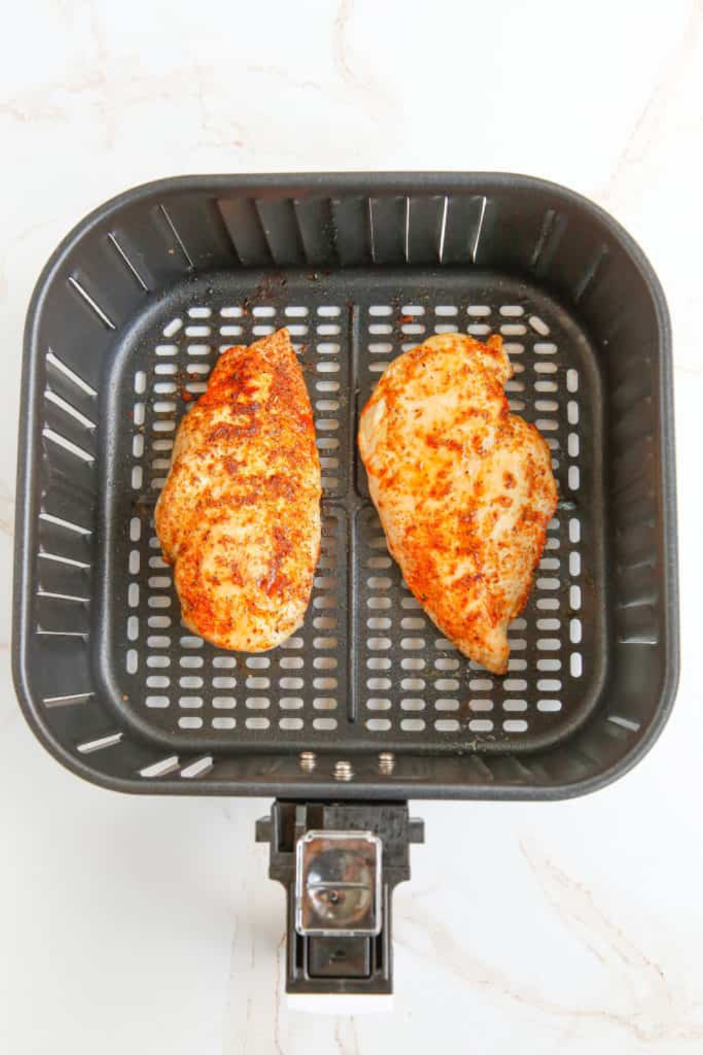 Herb-crusted chicken breasts arranged on a baking sheet, ready to go into the oven. or air fryer