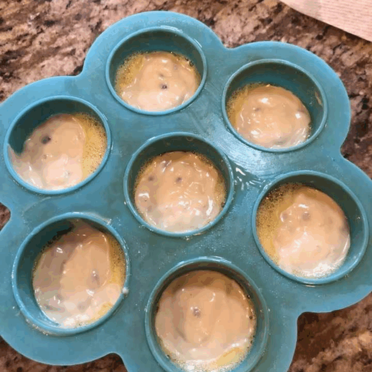 Blueberry muffin cups cooking in the air fryer basket until golden and fluffy