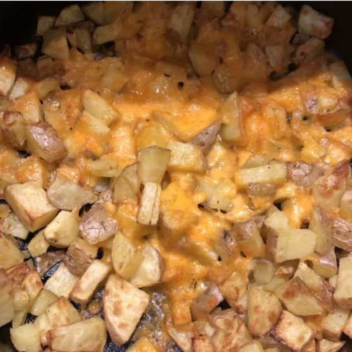 Potatoes tossed with olive oil, salt, and black pepper, arranged in a single layer in the air fryer basket.