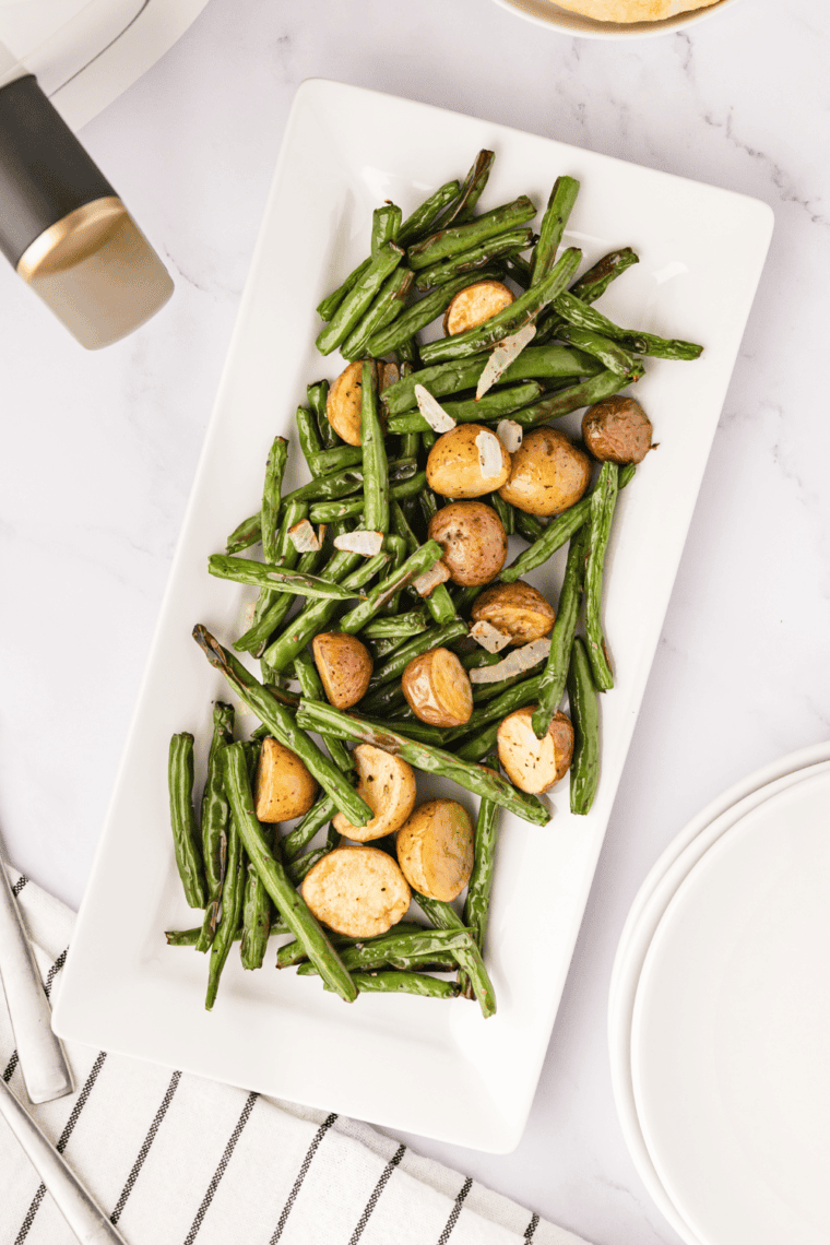 Air-fried green beans and golden potatoes served crispy on a plate with a sprinkle of herbs.