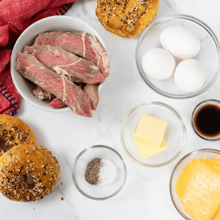Ingredients for an air fryer bagel breakfast sandwich: homemade bagel, egg, sausage patty, and cheese