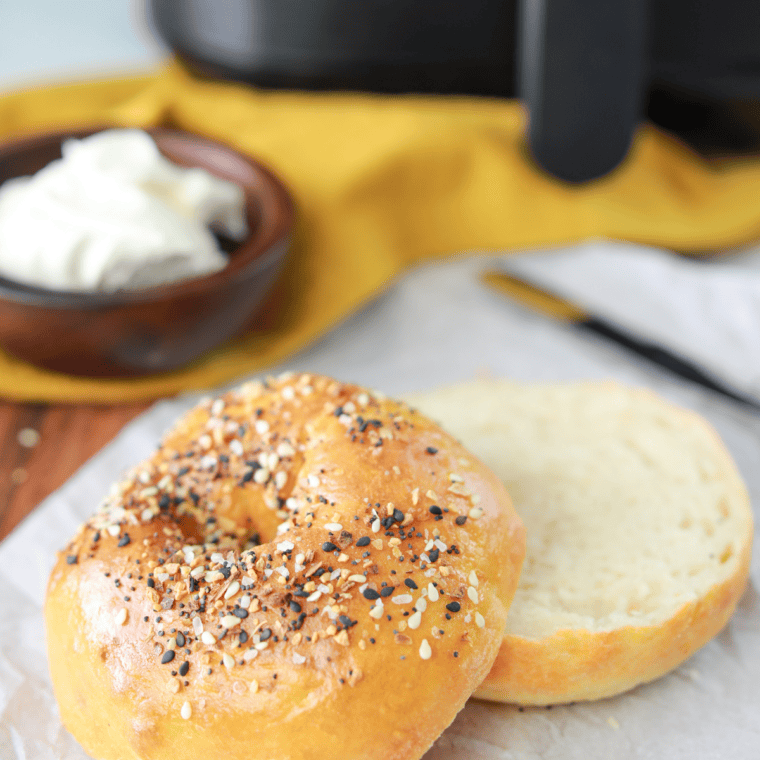 Halved homemade bagel and an egg in a ramekin placed in the air fryer basket at 330°F