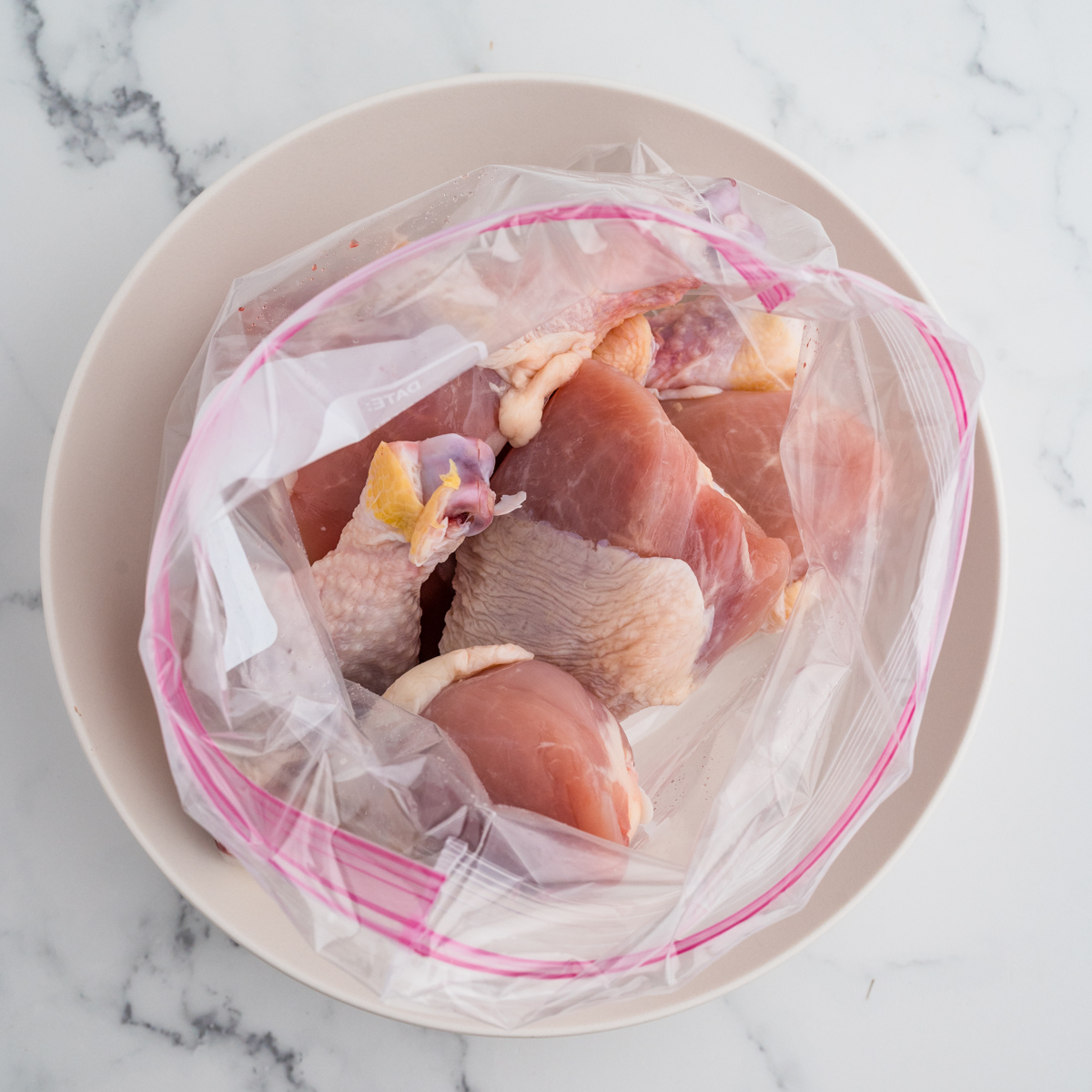 Chicken drumsticks in a Ziploc bag with soy sauce, honey, rice wine, sesame oil, and grated ginger, ready for marinating.