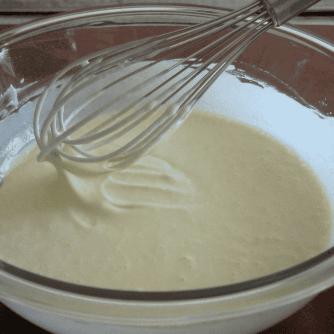 Mixing blueberry muffin batter with egg and milk in a large bowl