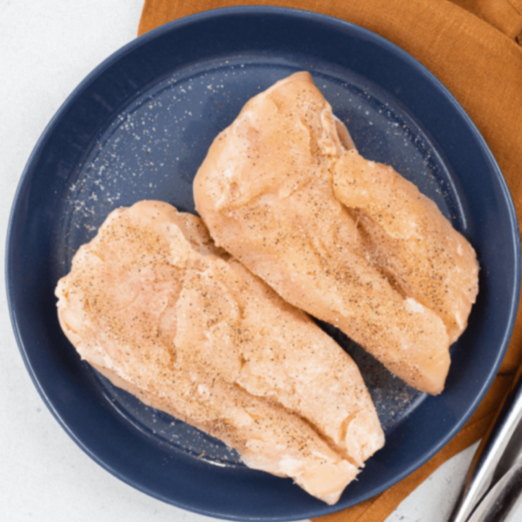 Hand pressing finely diced pecans into a seasoned chicken breast before air frying