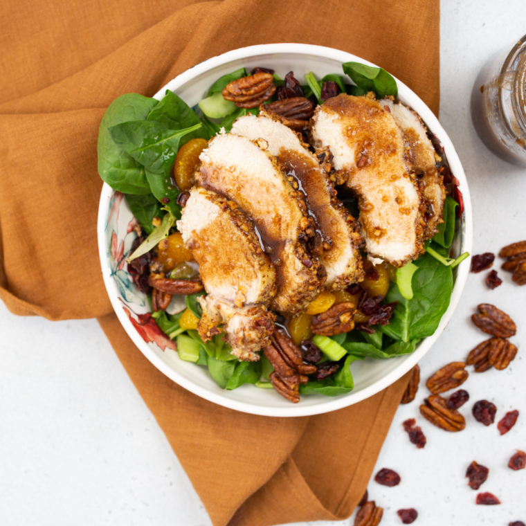 Bowl of Wendy's apple pecan chicken salad drizzled with homemade pomegranate vinaigrette.