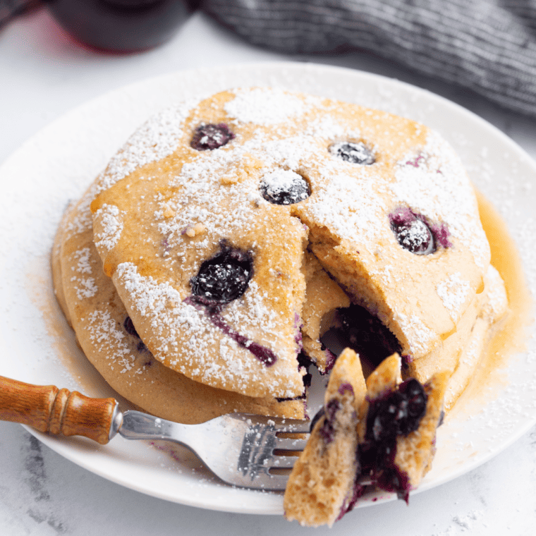 Homemade blueberry pancakes cooking inside an air fryer basket until golden brown