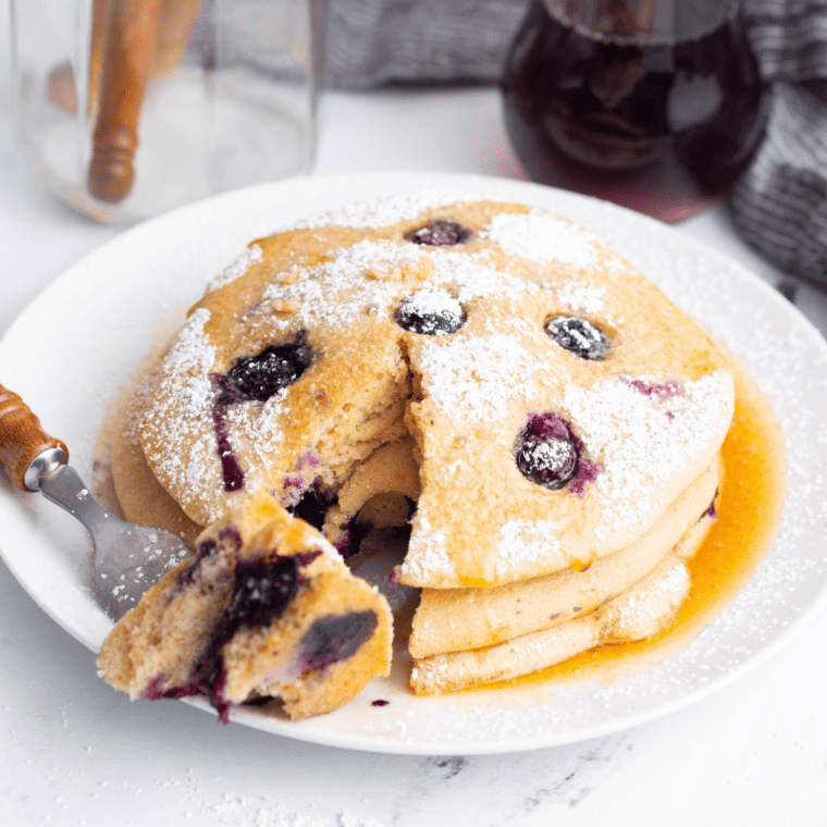Fluffy air fryer blueberry pancakes stacked with blueberries and maple syrup