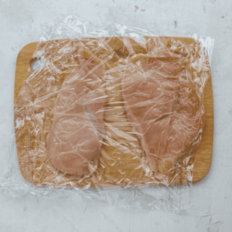 Air fryer basket sprayed with cooking spray, raw chicken breasts halved, pounded thin, and seasoned with garlic powder, salt, and black pepper.