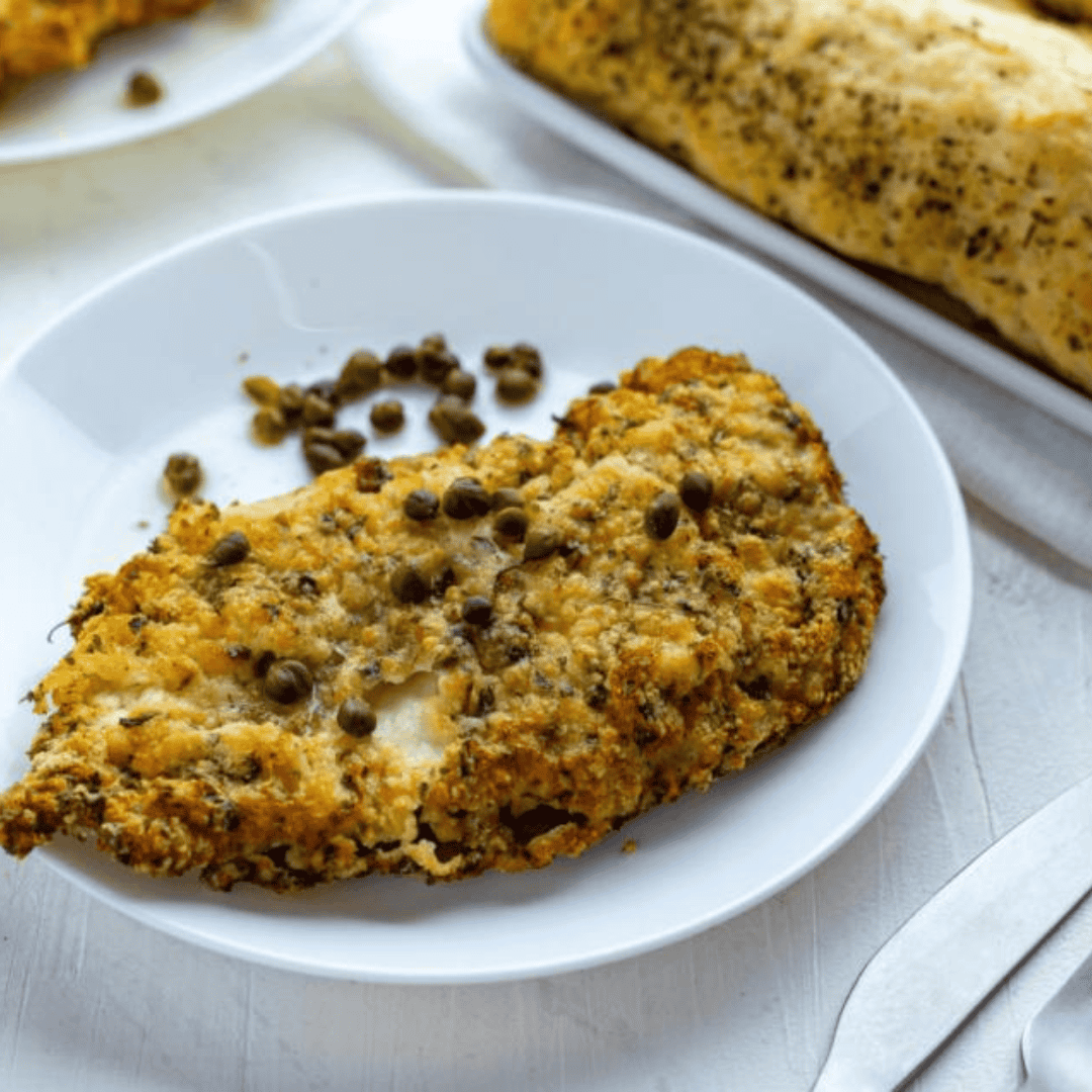 Air fryer chicken piccata served on a plate with lemon slices and capers, ready to enjoy.