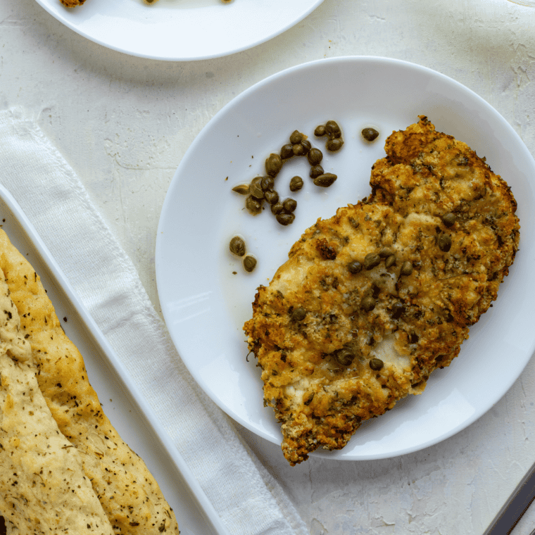 Air Fryer Chicken Piccata featuring golden-brown tender chicken breasts topped with lemon-caper sauce on a plate.