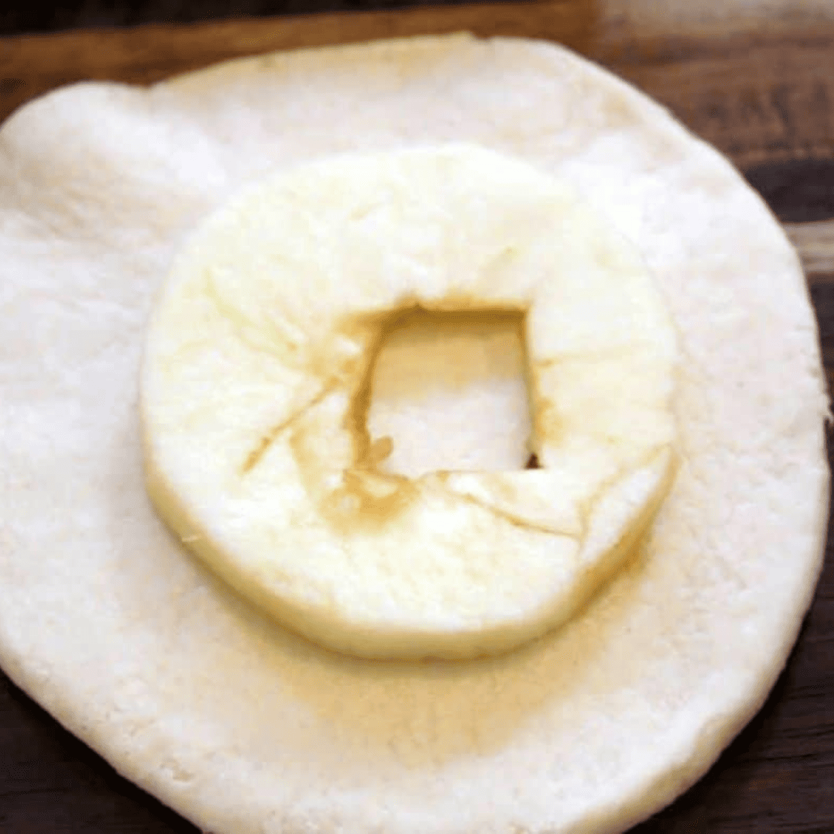 Apple slices and cinnamon sugar being wrapped inside rolled-out biscuit dough