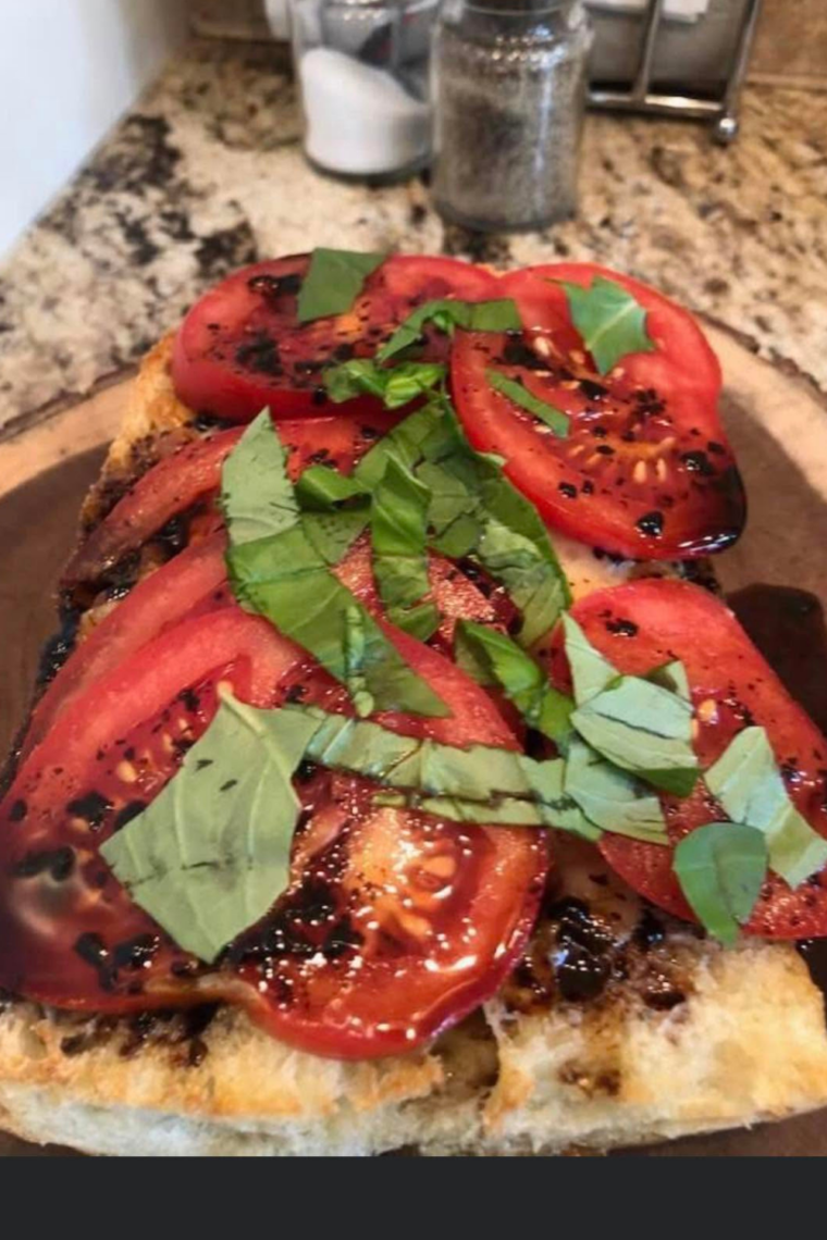 Air fryer caprese garlic bread topped with melted mozzarella, sliced tomatoes, fresh basil, and balsamic glaze