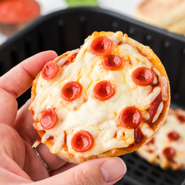 Close-up of an air fryer English muffin pizza showing bubbly cheese and crispy toasted edges