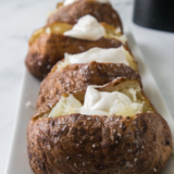 Air fryer jacket potato split open with butter melting into the fluffy middle