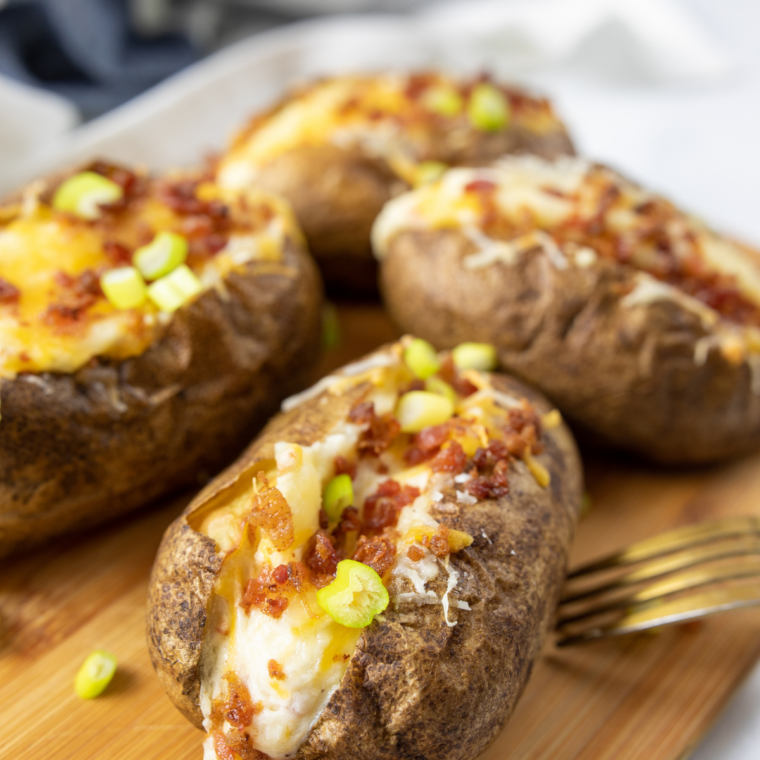 Air fryer jacket potato topped with baked beans and grated cheddar on a white plate