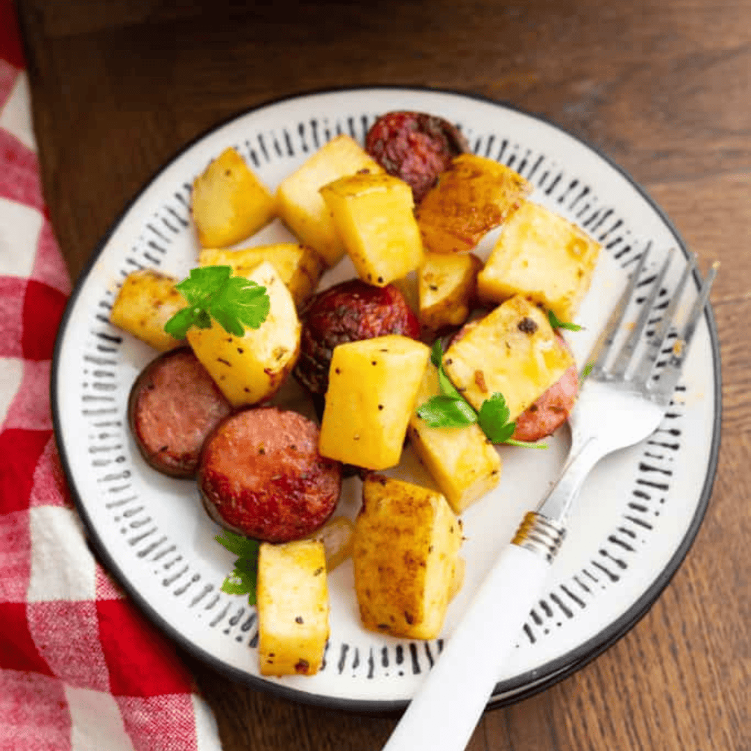 Crispy air fryer kielbasa and potatoes served in a white bowl, garnished and ready to eat.