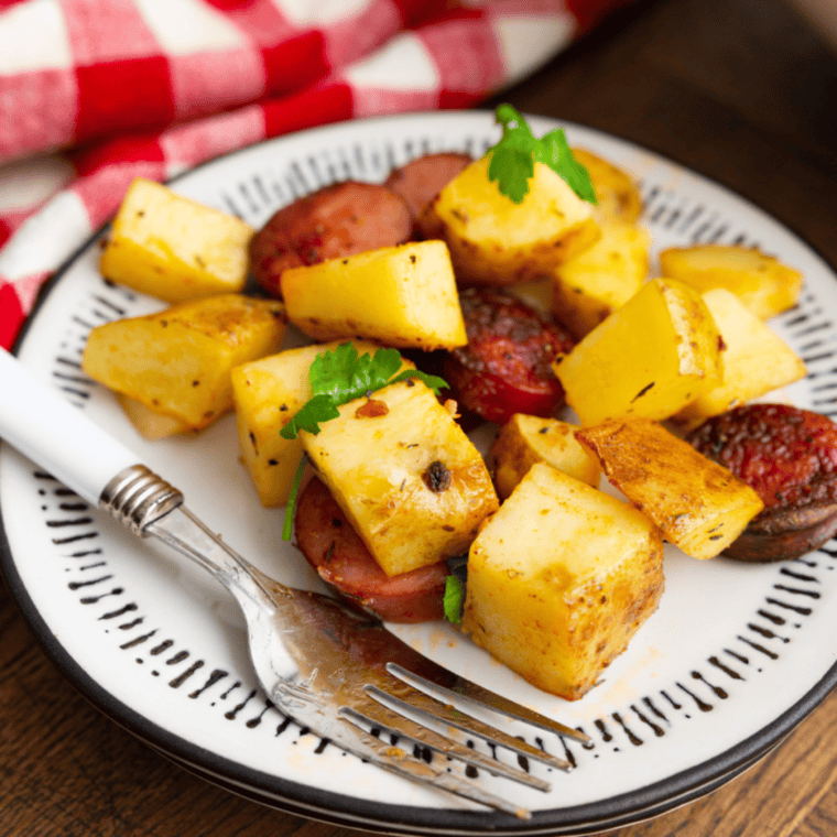 Air fryer kielbasa and potatoes in basket cooked until golden and crisp.