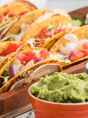 Air fryer steak tacos filled with sliced marinated ribeye, topped with lettuce, tomato, and cheese in warm tortillas