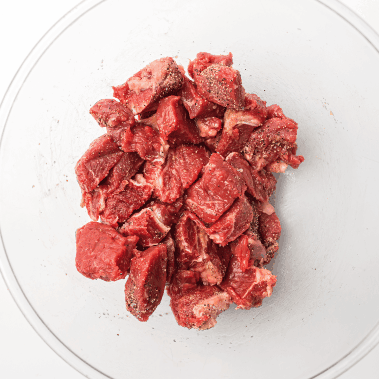 Steak tips coated in bourbon marinade in a resealable bag ready to refrigerate