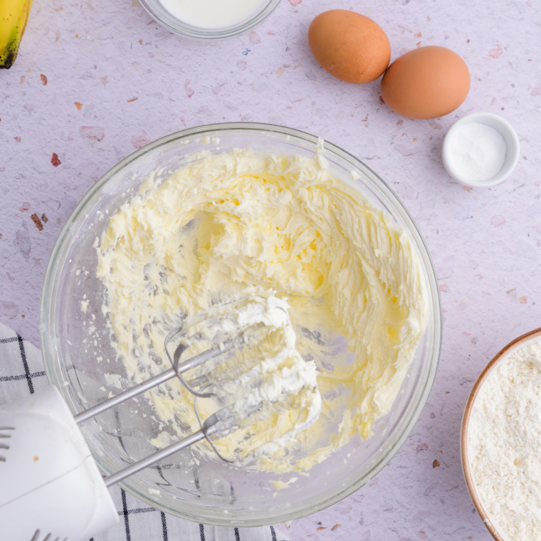 Mashed ripe bananas whisked with melted butter, brown sugar, and eggs in a mixing bowl