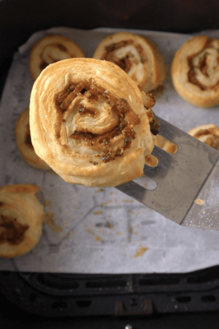 Crispy air fryer breakfast pinwheels filled with bacon, cheddar cheese, and brown sugar, stacked on a white plate