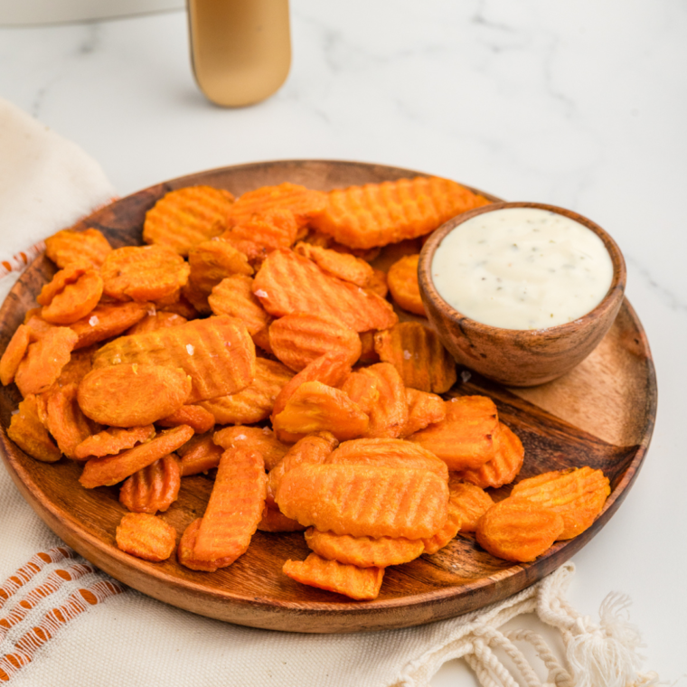 A plate of golden-brown air-fried carrot chips served with a tasty dip on the side.