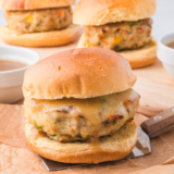 Two air fryer chicken burgers on toasted brioche buns with lettuce, tomato, and red onion