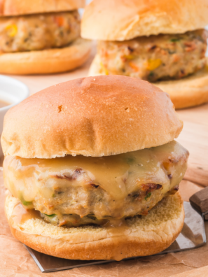 Two air fryer chicken burgers on toasted brioche buns with lettuce, tomato, and red onion