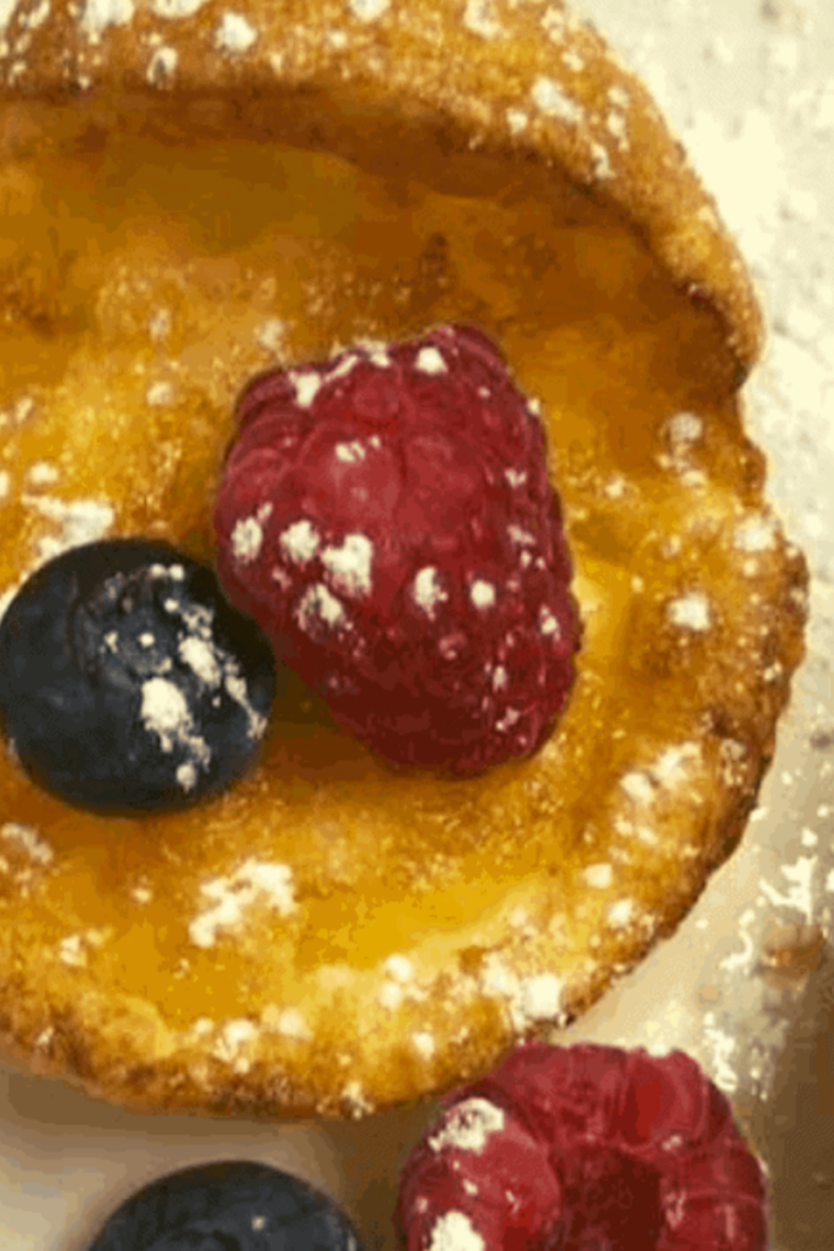 Stack of mini Dutch pancakes topped with syrup and berries with crisp golden edges