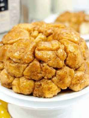 Air fryer monkey bread on a white plate with caramelized brown sugar glaze dripping down the pull-apart biscuit pieces