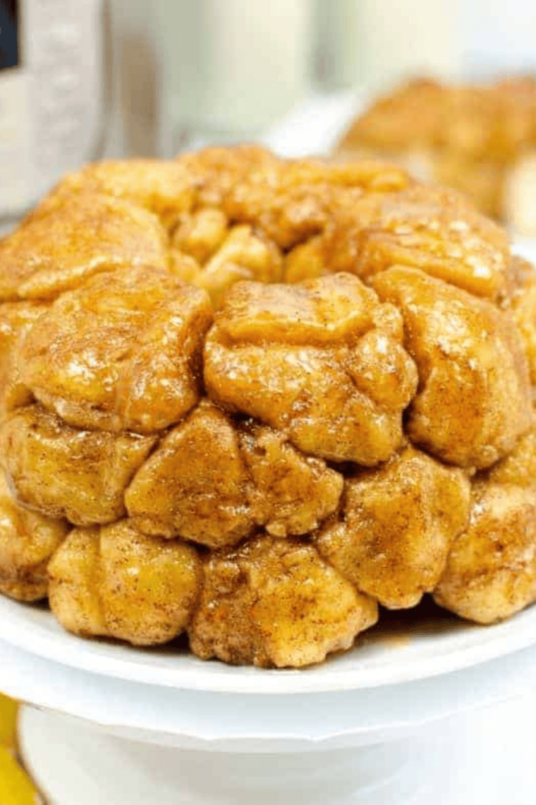 Air fryer monkey bread on a white plate with caramelized brown sugar glaze dripping down the pull-apart biscuit pieces