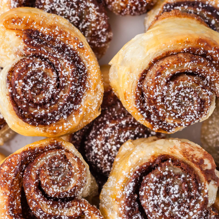 Air fryer Nutella puff pastry bites served on a white plate and dusted with powdered sugar
