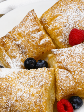 Air fryer puff pastry French toast squares dusted with powdered sugar and topped with fresh berries