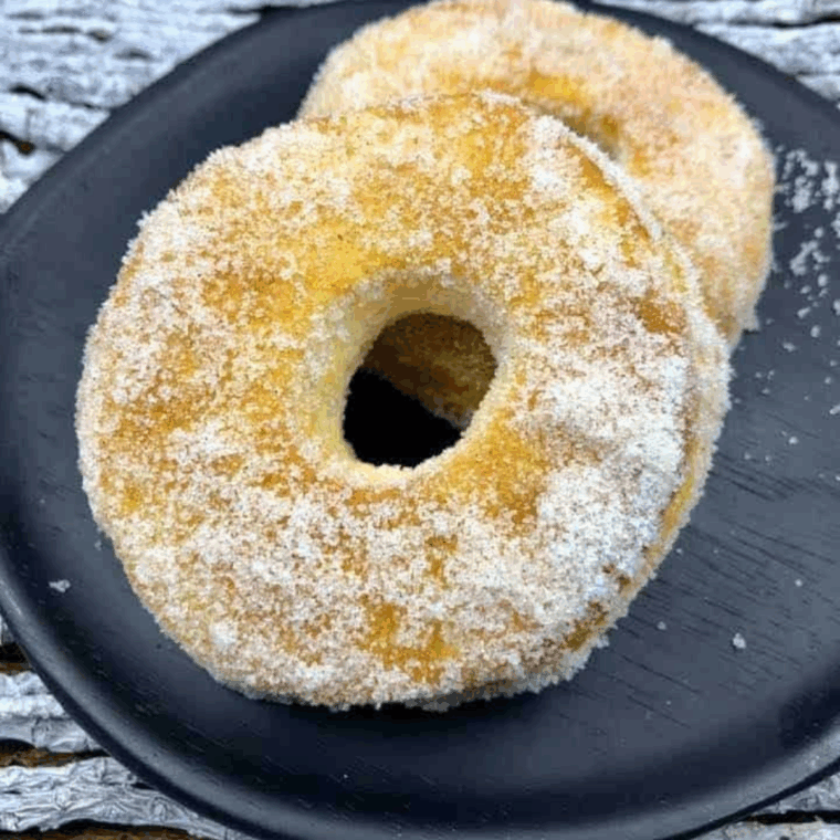 Cinnamon sugar air fryer biscuit donuts stacked on a white plate, golden with a crackly cinnamon crust