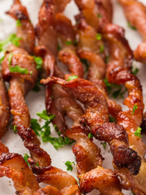 Crispy strips of Ninja Crispi bacon resting on the crisper plate inside the glass container, PowerPod lifted above