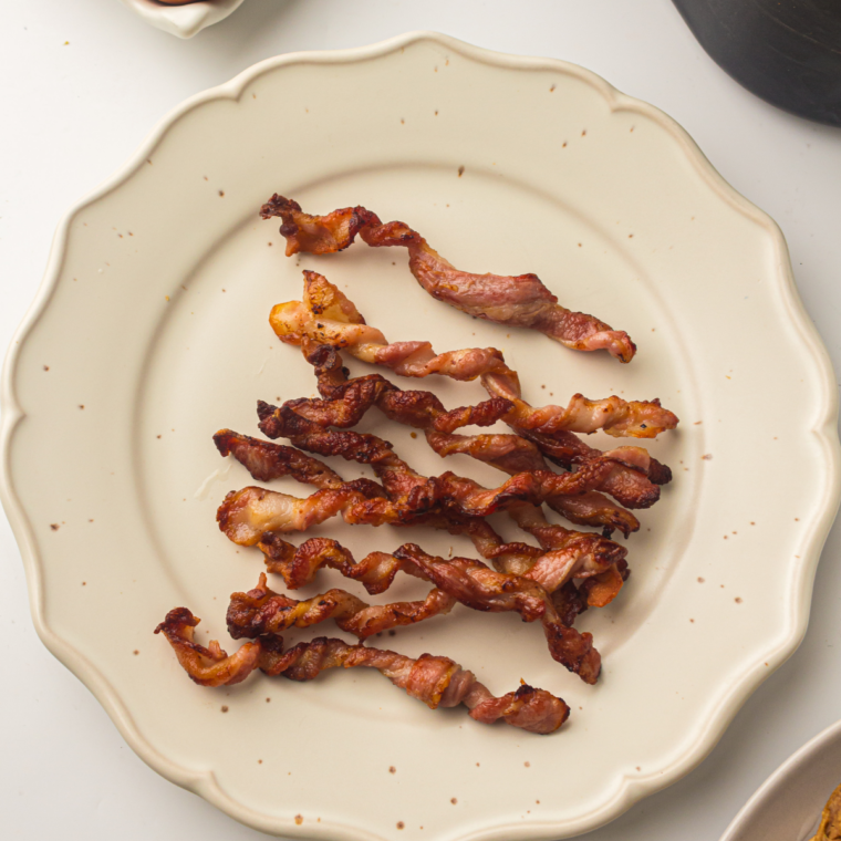 Six half-strips of bacon arranged in a single layer on the Ninja Crispi crisper plate