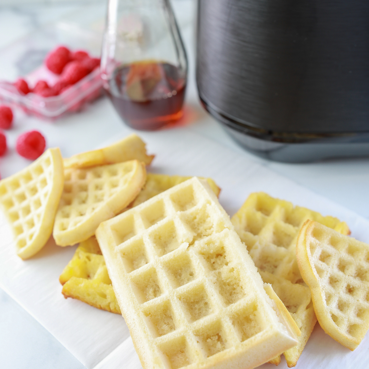 Fluffy, golden homemade waffles made in the air fryer, served on a plate with butter and syrup.