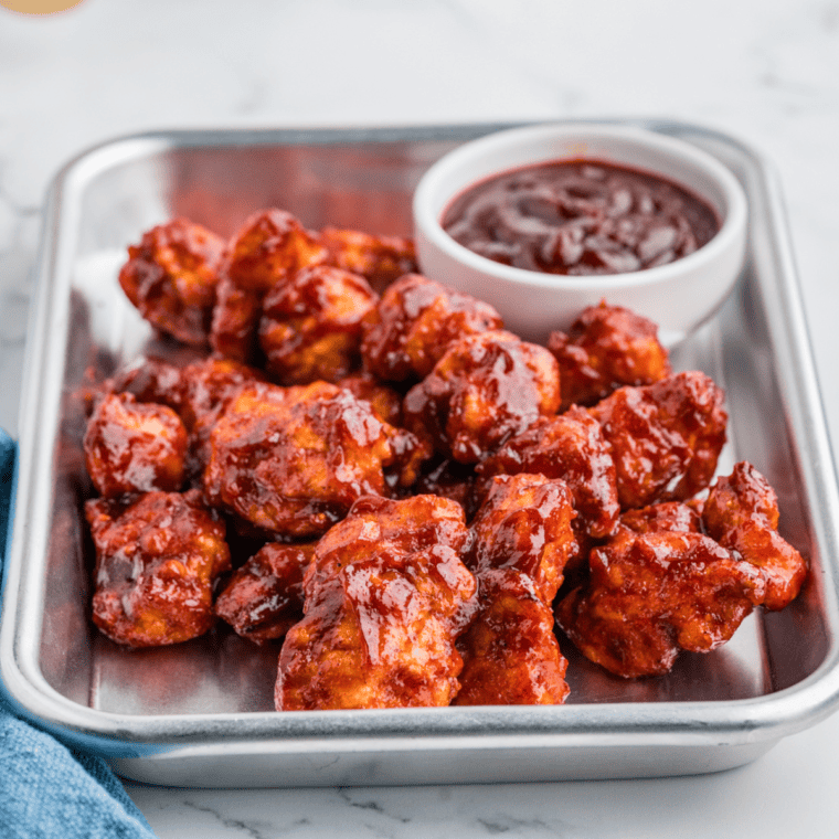 Air Fryer Honey BBQ Boneless Wings coated in sticky sauce, served on a white plate with dipping sauce.