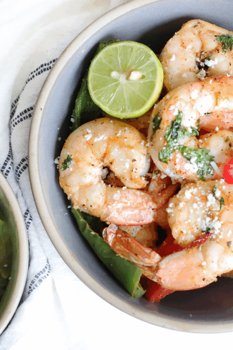 Air fryer pesto shrimp garnished with fresh basil and grated Parmesan